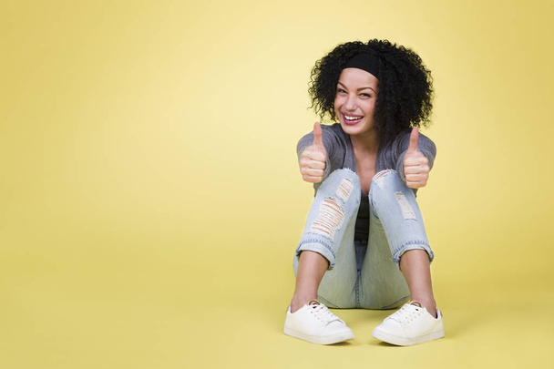 Success concept with woman: Successful happy woman with thumbs up being excited on isolated yellow background with empty copy space. - Photo, image