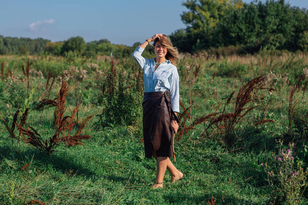 Happy young beautiful woman walking in a green field - Foto, Bild