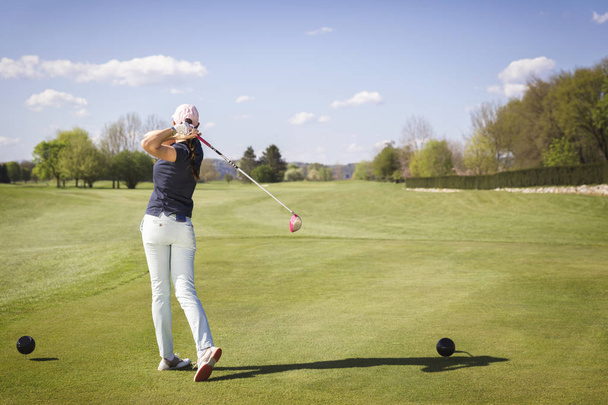 Female golf player swinging club. - Foto, imagen