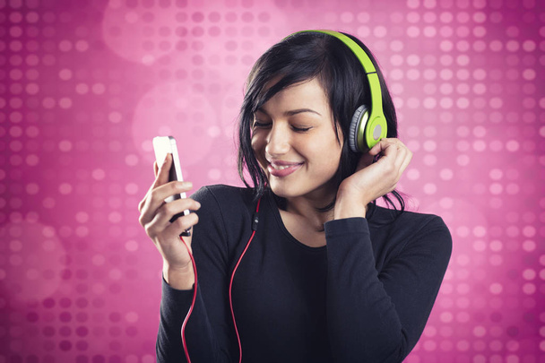 Friendly smiling girl listening to music with earphones. - Foto, Bild