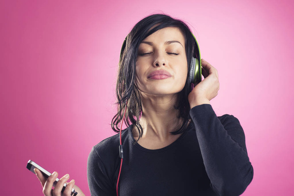 Smiling calm girl enjoying listening to music with headphones. - Fotografie, Obrázek