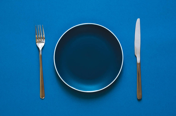 Color plate fork and knife isolated on blue background.  - Fotó, kép