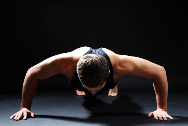 Handsome young muscular sportsman, on dark background - Valokuva, kuva