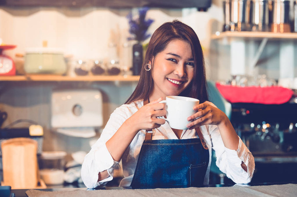 Asian female barista making cup of coffee. Young woman holding w - Fotografie, Obrázek