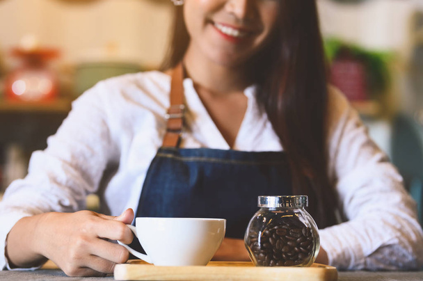 Closeup de xícara de café branco com bela mulher asiática barista b
 - Foto, Imagem