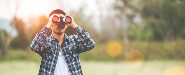 Hombre con telescopio binoculares en el bosque que mira destino como l
 - Foto, Imagen
