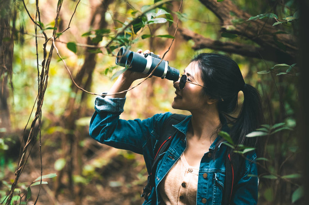 Όμορφη Ασιατική γυναίκα με κιάλια τηλεσκόπιο στο δάσος κοιτάζει - Φωτογραφία, εικόνα