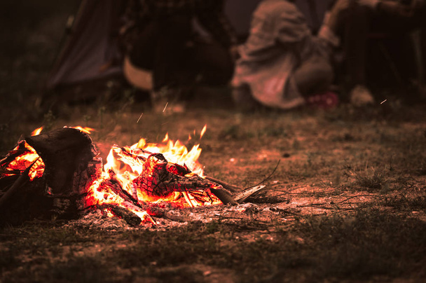 Iskrzenie ognisku z turystą siedzą wokół jasnego ognisko n - Zdjęcie, obraz