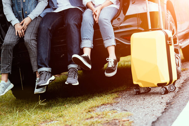 Closeup lower body of group of friends relaxing on SUV car trunk - Photo, Image
