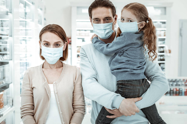 Family in the drugstore wearing a medical face mask - Foto, imagen