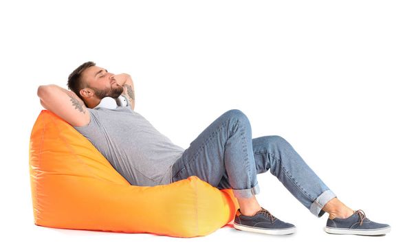 Handsome young man relaxing on beanbag against white background - Photo, Image