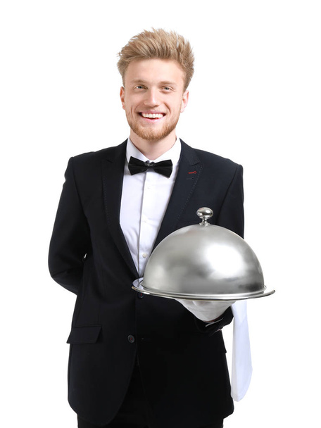 Knappe kelner met lade en cloche op witte achtergrond - Foto, afbeelding