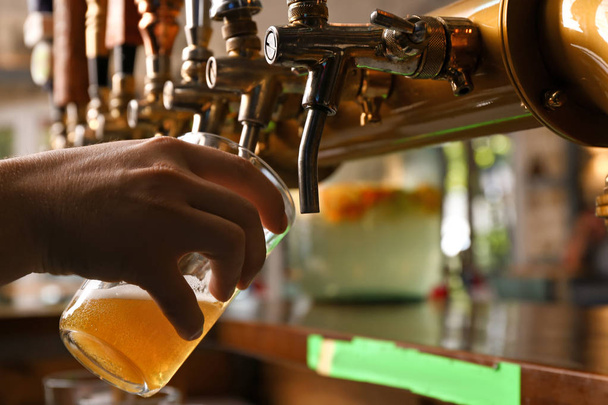 Barman pouring fresh beer in glass, closeup - Foto, imagen