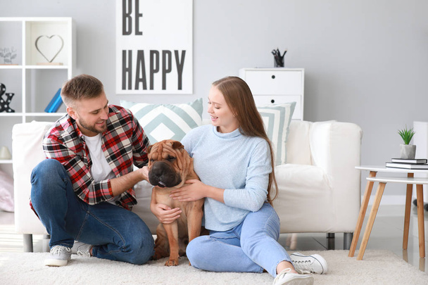 glückliches Paar mit niedlichem Hund zu Hause - Foto, Bild