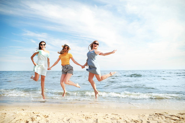 Gelukkig springen jonge vrouwen op zee strand in Resort - Foto, afbeelding
