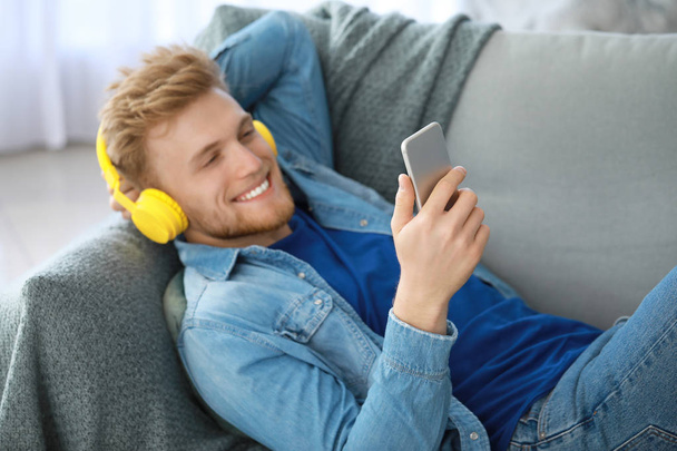 Schöner junger Mann hört zu Hause Musik - Foto, Bild