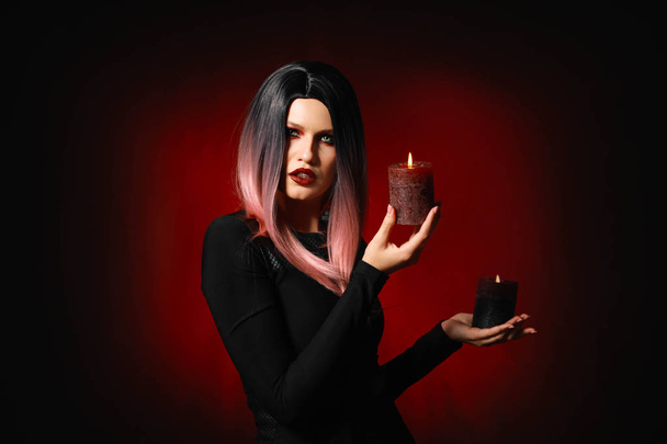 Beautiful woman with candles dressed for Halloween on dark background - Photo, Image