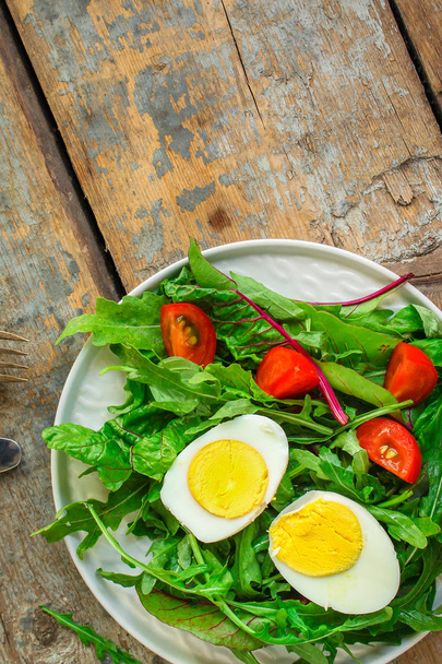 gezonde salade met gekookt ei, mix sla bladeren, tomaat, aperitief, snack. voedsel achtergrond. bovenaanzicht. ruimte kopiëren - Foto, afbeelding