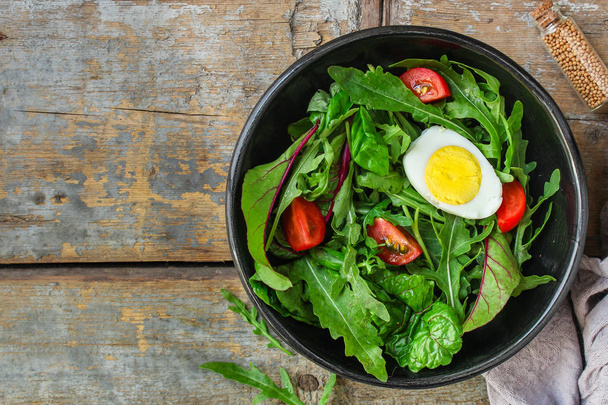 ゆで卵、レタスの葉、トマト、前菜、スナックを混ぜたヘルシーなサラダ。食べ物の背景。トップビュー。コピースペース - 写真・画像
