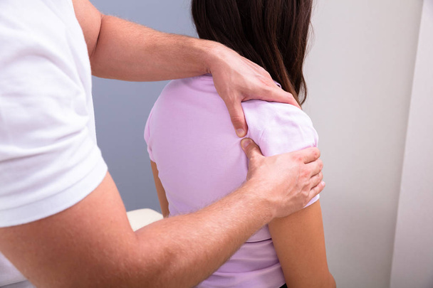 Professional Male Physical Therapist Massaging The Injured Shoulder Of A Woman Slowly In Medical Clinic - Zdjęcie, obraz