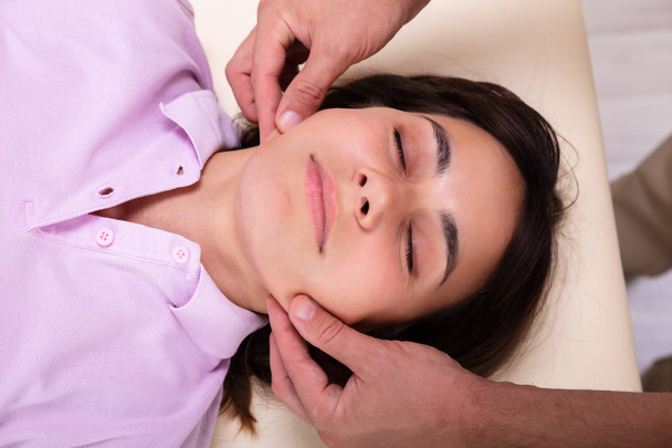 Close-up Of A Relaxed Young Woman Receiving Jaw Massage From Physiotherapist In Clinic - Fotoğraf, Görsel