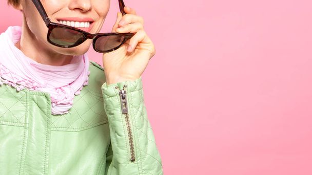 Beautiful spring woman wearing sunglasses, mint jacket over pink background - Foto, afbeelding