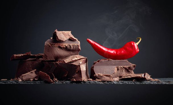 Μαύρη σοκολάτα με κόκκινη πιπεριά σε σκούρο φόντο.  - Φωτογραφία, εικόνα