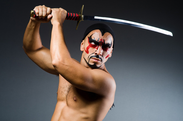 man met zwaard en gezicht verf - Foto, afbeelding