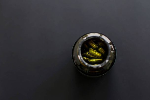 Spirulina-Kapseln in Glasflasche auf schwarzem, dunklem Hintergrund. flach - Foto, Bild
