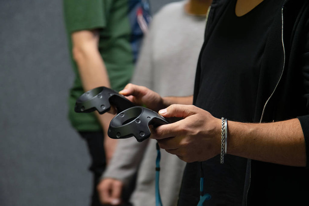 Молодий чоловік грає у віртуальну реальність, одягаючи гарнітуру та тримаючи ігровий майданчик контролера в руках
 - Фото, зображення