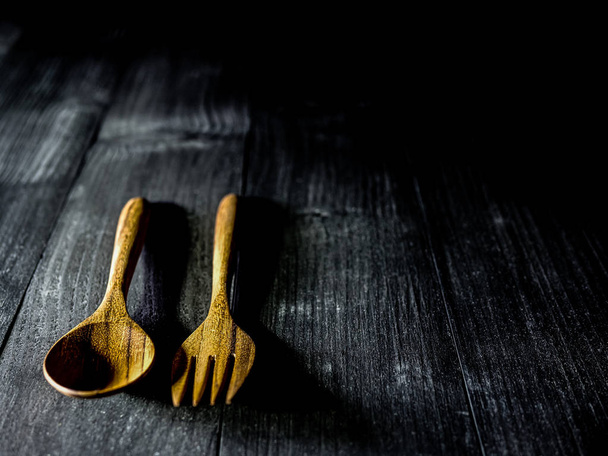 Wooden spoon and fork on a dark wooden table with dim light, sel - Photo, Image