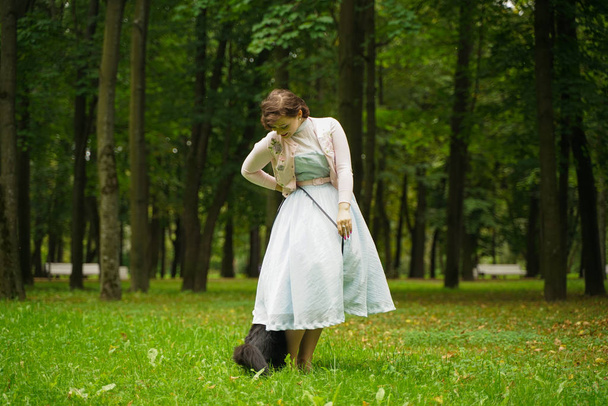 Piękny zabytkowe kobieta chodzenie z jej czarny kot Maine Coon w The Park - Zdjęcie, obraz