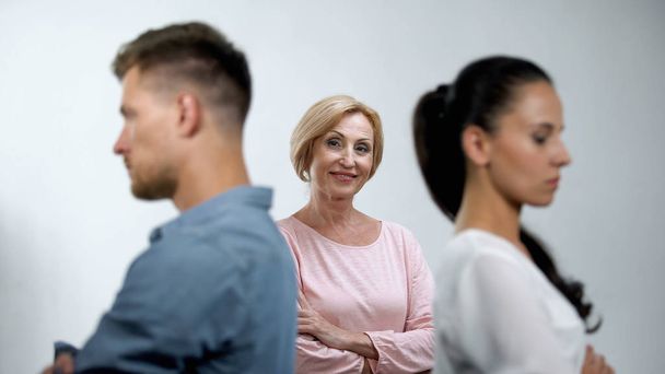 Satisfied mother looking at couple in quarrel standing back to each other - Photo, image