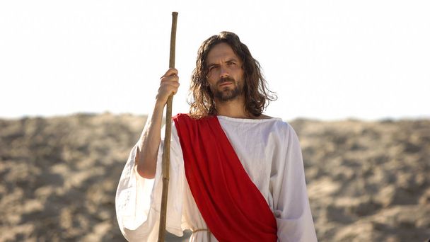 Jesus with wooden staff standing in desert, preaching Christian faith conversion - 写真・画像