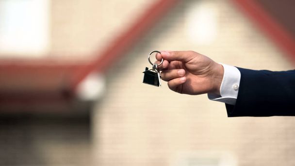 Real estate manager hand giving house key, purchasing and selling property - Foto, Bild