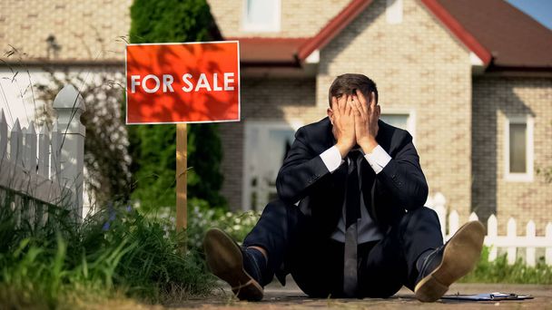 Extremely upset real estate manager sitting by for sale signboard, failed deal - Φωτογραφία, εικόνα