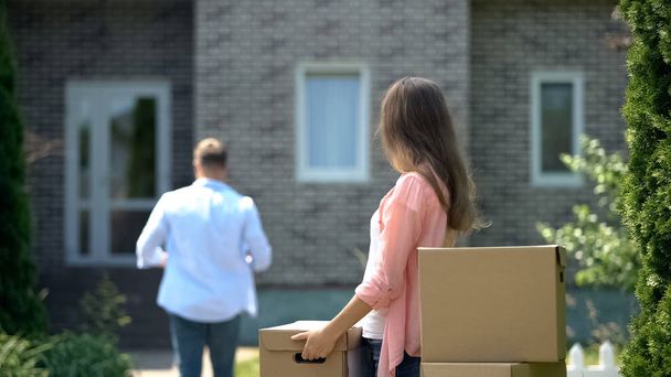 Семья переезжает в новый дом, муж несет тяжелые картонные коробки, аренда
 - Фото, изображение