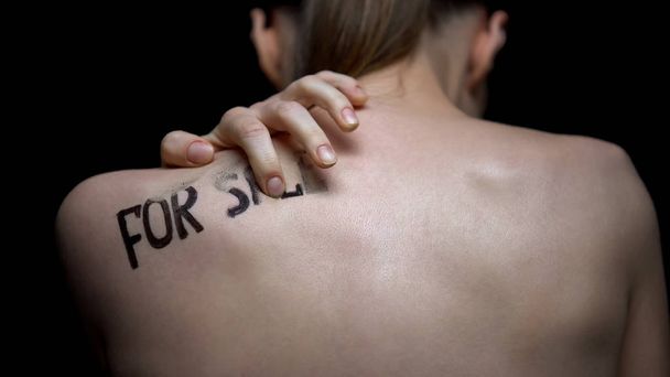 Frightened naked woman wiping for sale phrase from shoulder, human trafficking - Foto, Bild