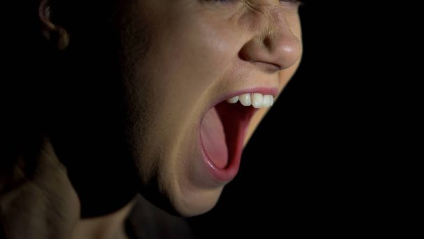 Face of female screaming against dark background, psychological problems - Φωτογραφία, εικόνα