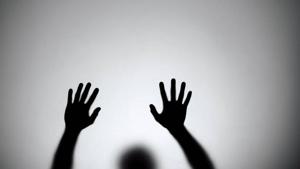 Silhouette of hands sliding down glass wall, person dying, crime scene, horror - Fotografie, Obrázek