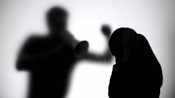 Silhouette of man shouting on crying woman in megaphone, family problems - Photo, image