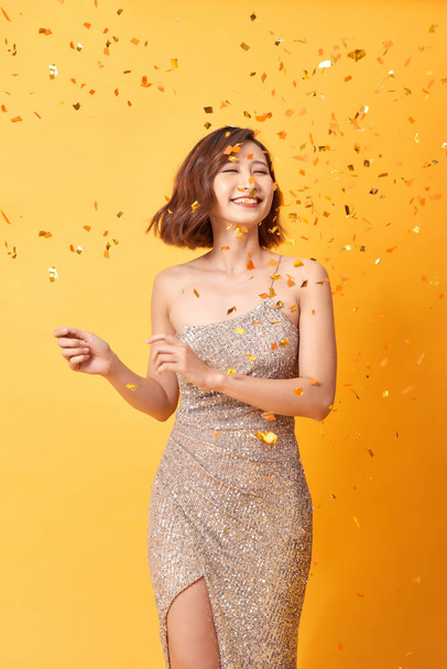 bela mulher sexy em vestido de noite comemorando, confete dourado, festa, sorrindo, convidando, feliz
 - Foto, Imagem