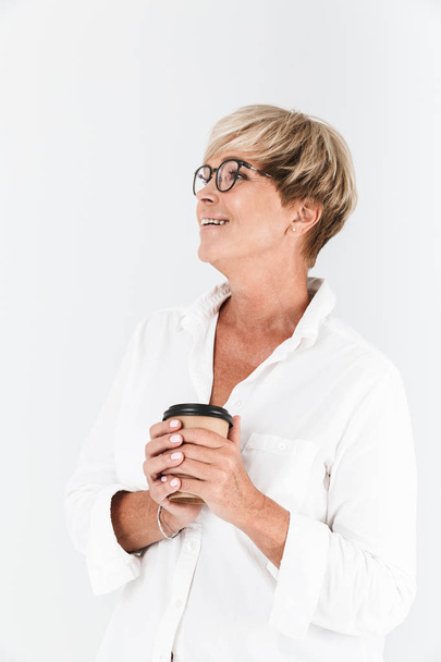 Portrait of positive adult woman wearing eyeglasses holding takeaway coffee cup - Zdjęcie, obraz