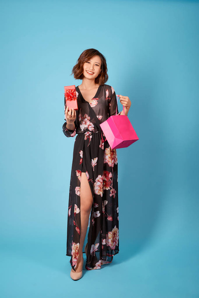 Despreocupado señora asiática posando después de ir de compras. Mujer adorable sosteniendo bolsas de tienda
. - Foto, Imagen