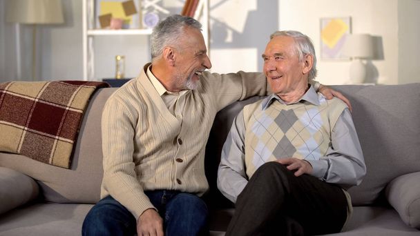 Smiling senior men looking each other sitting home sofa friendship communication - Photo, Image
