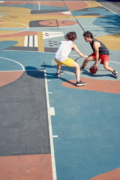 Top view image of two sportsmen playing basketball on playground in morning. - Valokuva, kuva