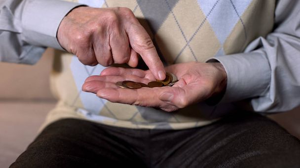Aged man counting coins in open palm, low income, social insecurity, close-up - Valokuva, kuva