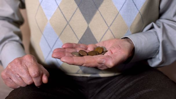 Mature man holding pound cents, old age poverty, pension insurance, credit - Fotó, kép