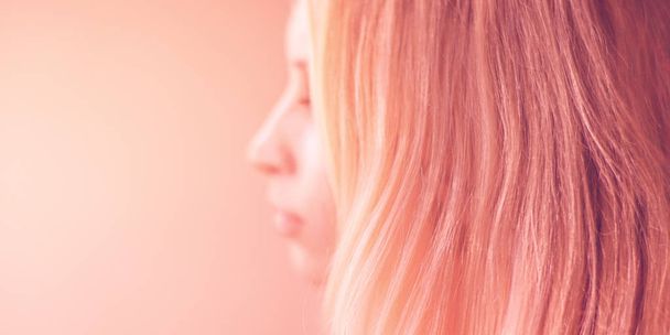 női rózsaszín szőr a pasztell háttérrel, oldalnézet álló, elmosódott arc. - Fotó, kép