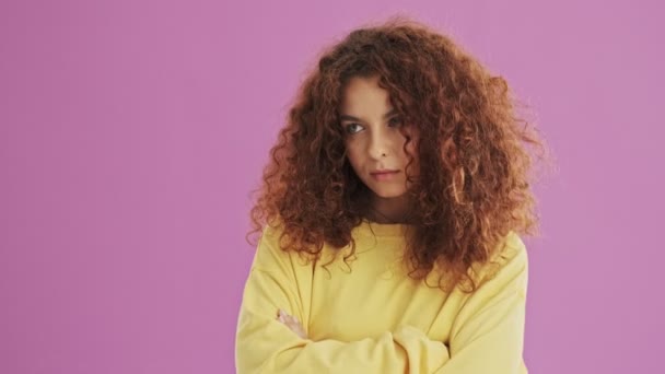 Upset young redhead curly woman crossed her arms and feeling sad over pink background isolated - Video